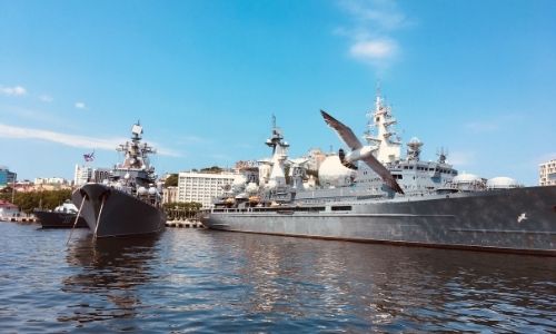  deux bateaux sur la mer avec un aigle au premier plan et des bâtiments au second plan 