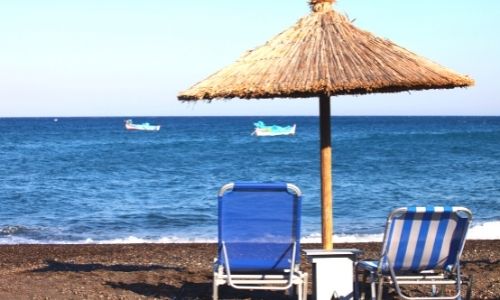 plage de Santorin avec un transat et un parasol en osier