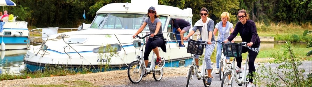 Promenade en famille à vélo en longeant le canal du midi avec un bateau sans permis