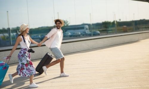 couple qui court avec leurs valises à la main dans un aéroport