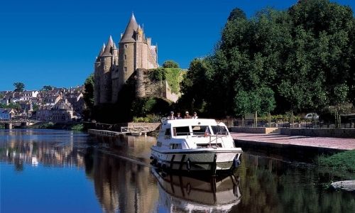 Un bateau sans permis passe devant la ville de Josselin et son bateau sans permis