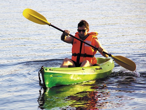 Un homme portant un gilet de sauvetage fait du canoë kayak sur une étendue d’eau