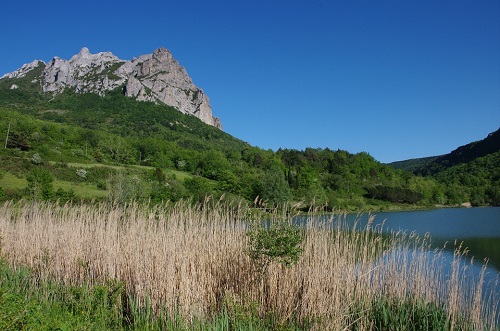 Le bord du lac affleure la montagne de Bugarach baigné dans un ciel bleu