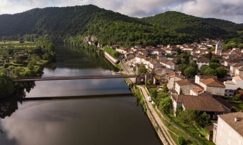 Une vue semi-aérienne du village de Douelle, du Lot et du pont suspendu qui le traverse