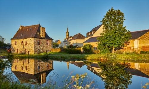 Les berges du village de Tinténiac, on peut apercevoir le clocher de l’église derrière les maisons en pierre.