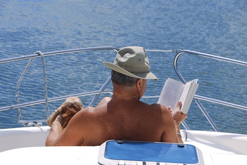 Un homme lit son livre sur le ponton du bateau