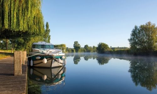 bateau sans permis à quai sur le côté gauche de l’image, sur une grande étendue d’eau en pleine nature