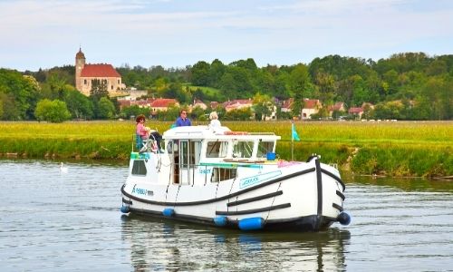péniche sur l’eau avec trois personnes qui profitent du voyage