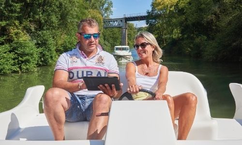 Un couple sur le poste de navigation extérieur de leur bateau sans permis