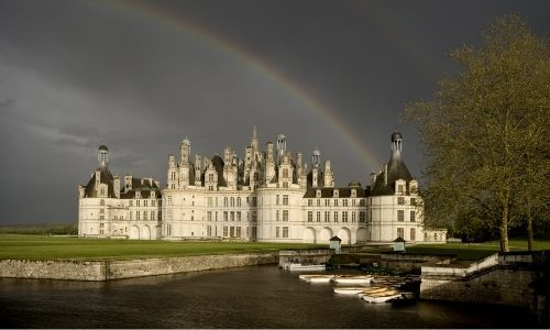 La château de Chambord perdu dans son vaste parc. Un arc en ciel culmine au-dessus du château.