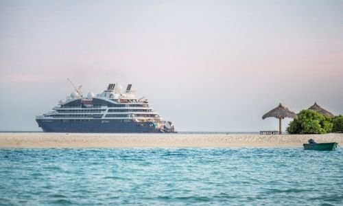 Le Jacques Cartier au loin et un plage paradisiaque au premier plan