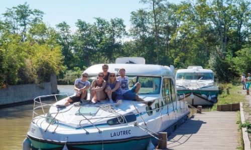 Un groupe d'amis sur le ponton principale d'un bateau sans permis se réuni pour une belle photo