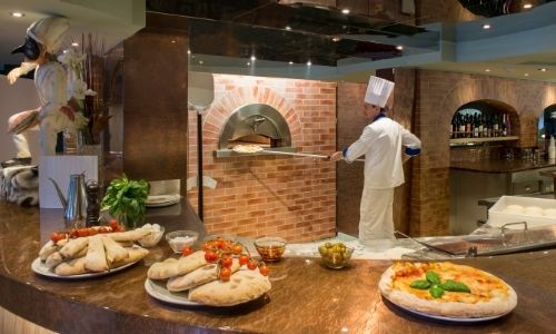 Pizzéria à bord d'un navire de croisière, un cuisinier enfourne des pizzas au four